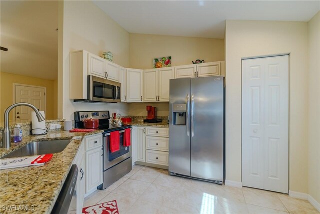 kitchen with stainless steel appliances, light stone countertops, sink, and light tile patterned floors