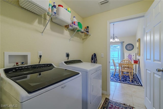 laundry room with light tile patterned flooring, washer and dryer, and a notable chandelier