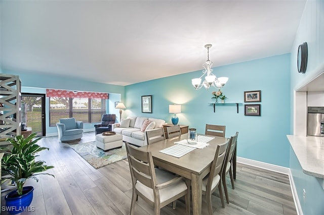 dining area with a notable chandelier, baseboards, and light wood-style floors