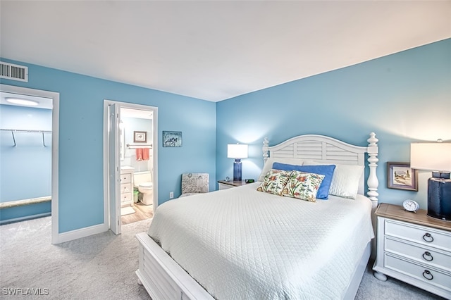 bedroom with ensuite bathroom, carpet floors, visible vents, baseboards, and a spacious closet