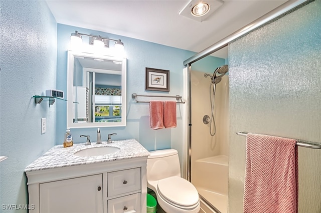 bathroom with toilet, a textured wall, a shower stall, and vanity