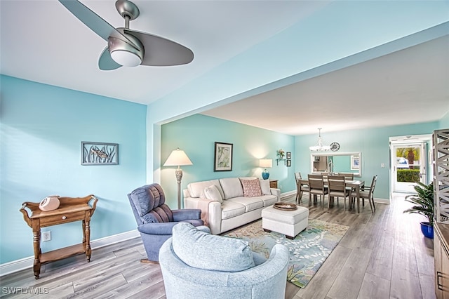 living area featuring ceiling fan, baseboards, and wood finished floors