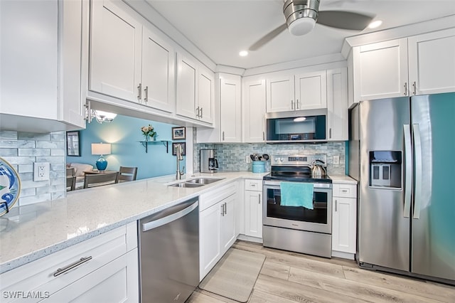 kitchen with appliances with stainless steel finishes, a ceiling fan, white cabinetry, a sink, and light wood-type flooring