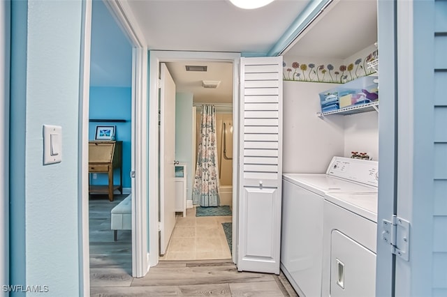 laundry room with laundry area, light wood-style flooring, visible vents, and washing machine and clothes dryer