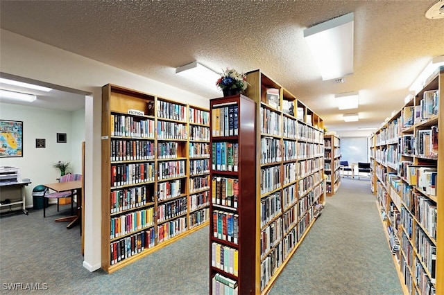 interior space with carpet floors, bookshelves, and a textured ceiling