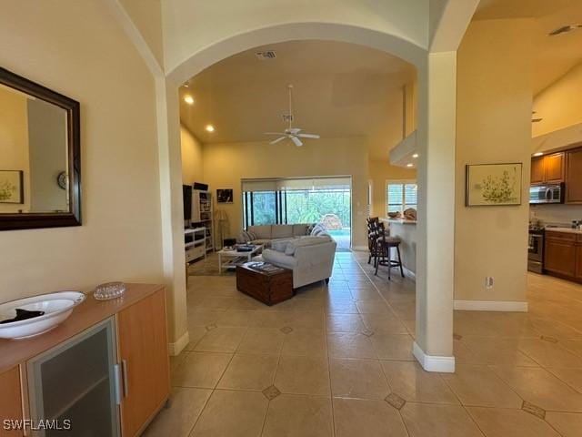 living room featuring ceiling fan, light tile patterned floors, and a towering ceiling