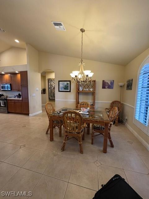 tiled dining room featuring vaulted ceiling and a notable chandelier