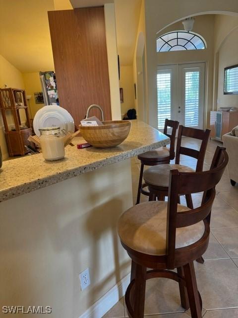 dining room featuring light tile patterned floors, lofted ceiling, and french doors