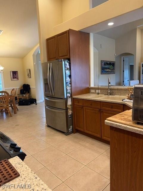 kitchen featuring a high ceiling, light tile patterned floors, stainless steel fridge, and a chandelier