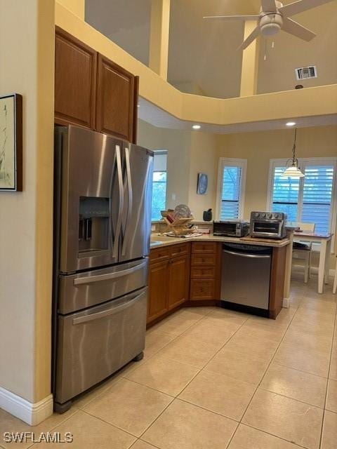 kitchen featuring ceiling fan, pendant lighting, a towering ceiling, stainless steel appliances, and light tile patterned floors