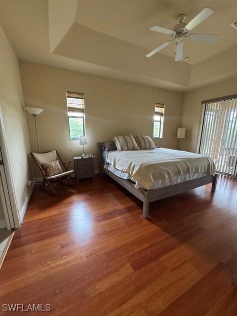 unfurnished bedroom featuring ceiling fan, dark wood-type flooring, and a raised ceiling