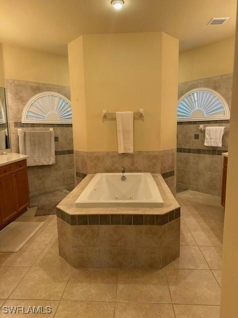 bathroom featuring tiled bath, vanity, tile patterned flooring, and tile walls