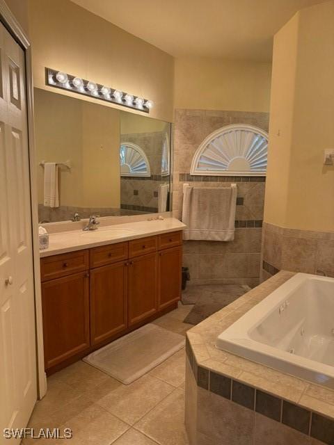 bathroom featuring tiled bath, vanity, and tile patterned flooring