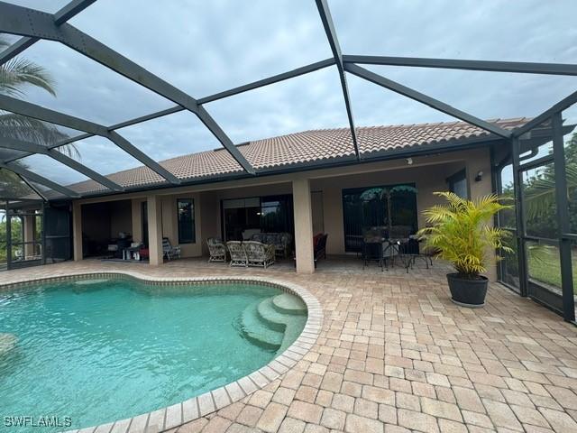 view of swimming pool with an outdoor living space, glass enclosure, and a patio