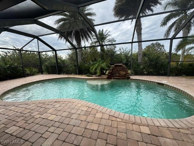 view of swimming pool with glass enclosure and a patio