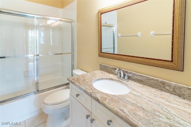 full bathroom with toilet, enclosed tub / shower combo, tile patterned flooring, and vanity