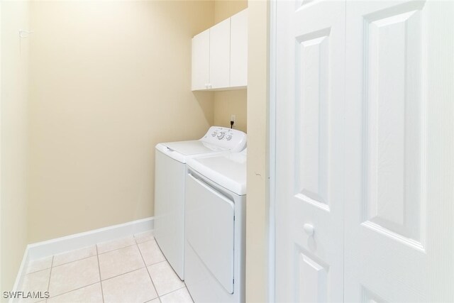 laundry area with washer and dryer, cabinets, and light tile patterned flooring