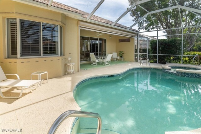 view of pool with ceiling fan, a patio, glass enclosure, and an in ground hot tub