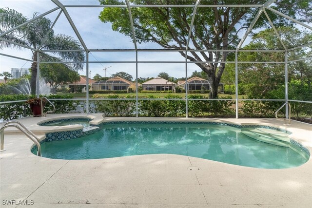 view of pool with a patio, glass enclosure, and an in ground hot tub