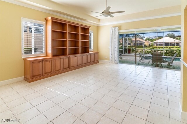 unfurnished room with a wealth of natural light, light tile patterned flooring, a tray ceiling, and ceiling fan