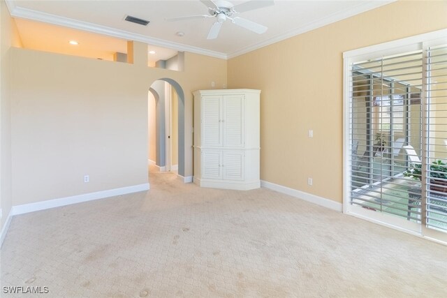 carpeted spare room with ceiling fan, a wealth of natural light, and ornamental molding