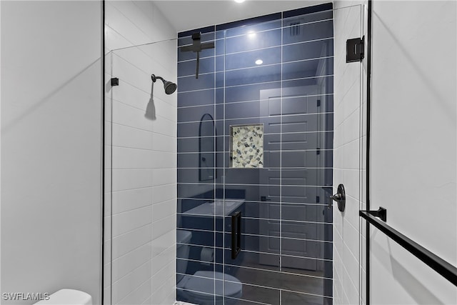 bathroom featuring a tile shower and toilet