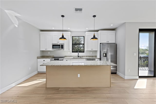 kitchen featuring light stone countertops, white cabinets, appliances with stainless steel finishes, and a kitchen island