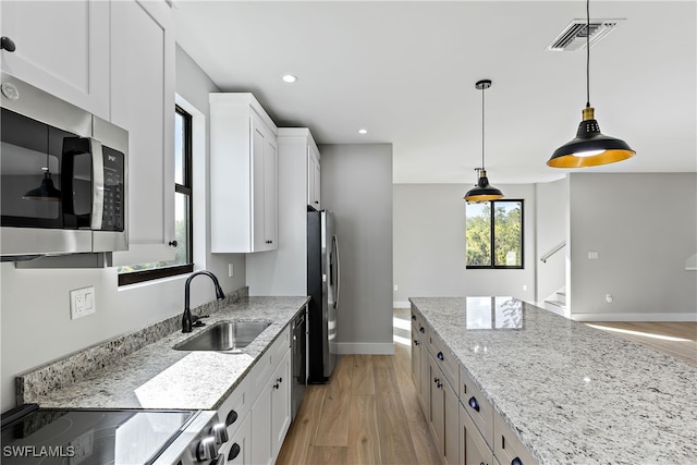 kitchen with white cabinets, light wood-type flooring, sink, stainless steel appliances, and light stone counters