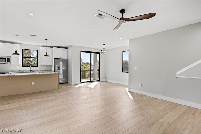 unfurnished living room with light wood-type flooring, ceiling fan, and sink