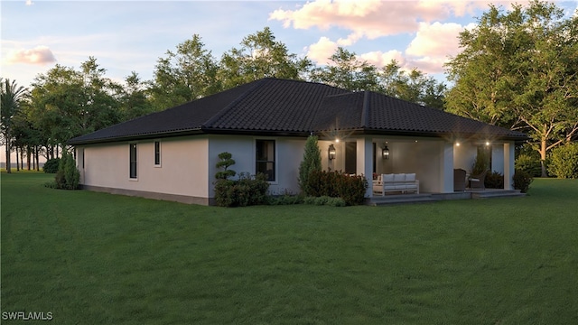 back house at dusk with a yard and outdoor lounge area