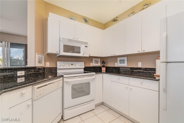 kitchen with dark stone countertops, light tile patterned floors, white appliances, and white cabinets