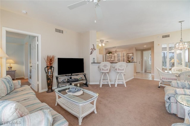 carpeted living room featuring ceiling fan with notable chandelier