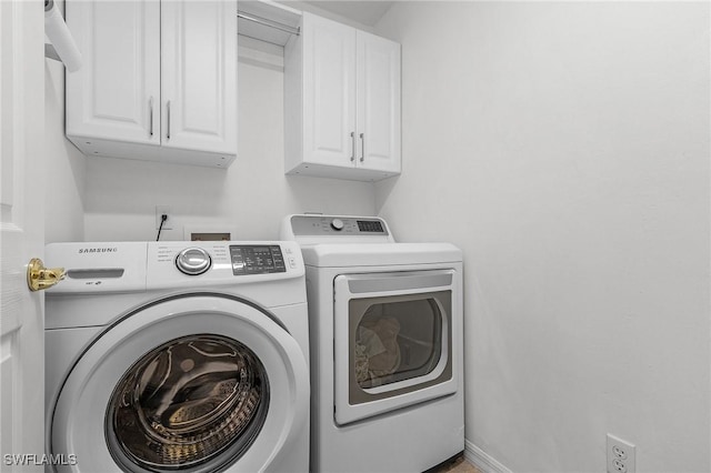 clothes washing area featuring cabinets and washer and clothes dryer