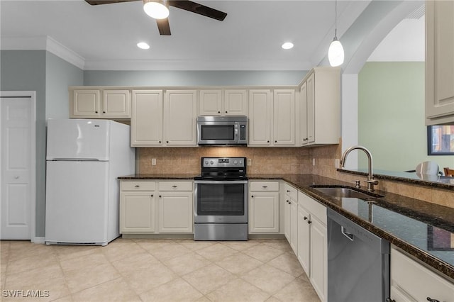 kitchen featuring sink, appliances with stainless steel finishes, dark stone countertops, ornamental molding, and decorative light fixtures