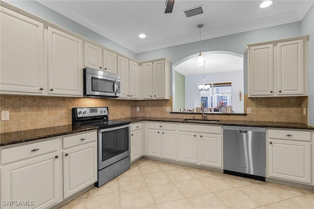 kitchen with pendant lighting, sink, appliances with stainless steel finishes, dark stone countertops, and decorative backsplash