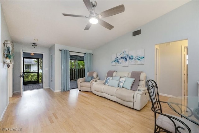 living area featuring lofted ceiling, light wood-type flooring, visible vents, and baseboards