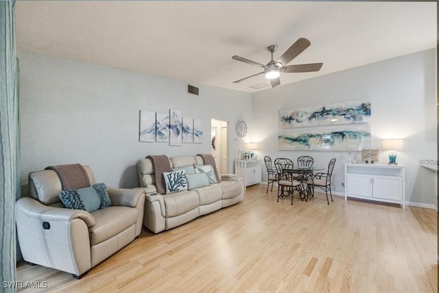 living area with light wood-type flooring, ceiling fan, visible vents, and baseboards