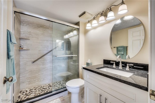 bathroom featuring toilet, vanity, and a shower with shower door