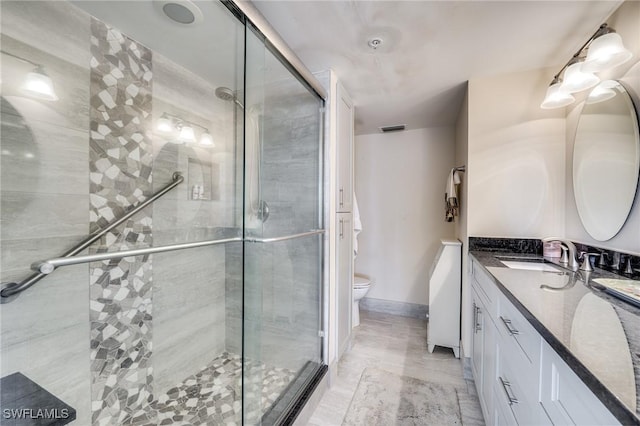 bathroom with a shower with door, vanity, and toilet