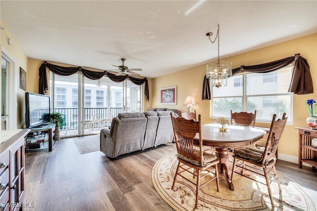 dining area featuring wood-type flooring and ceiling fan with notable chandelier