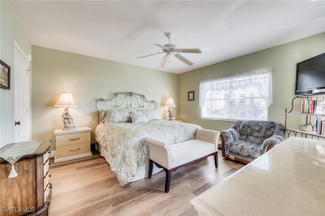 bedroom featuring ceiling fan, a textured ceiling, and light wood-type flooring