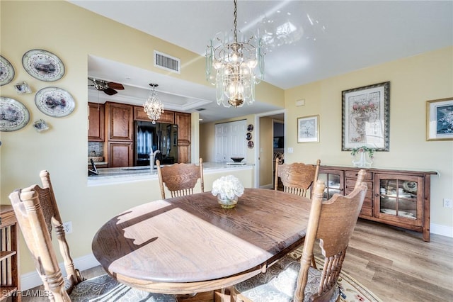 dining room with a tray ceiling, a chandelier, and light wood-type flooring