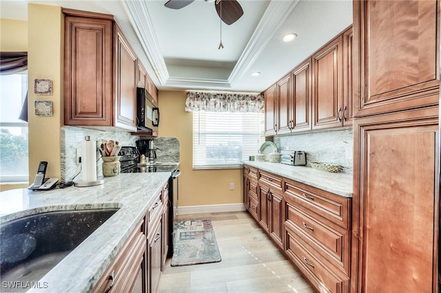 kitchen featuring a raised ceiling, ornamental molding, light stone countertops, and black appliances