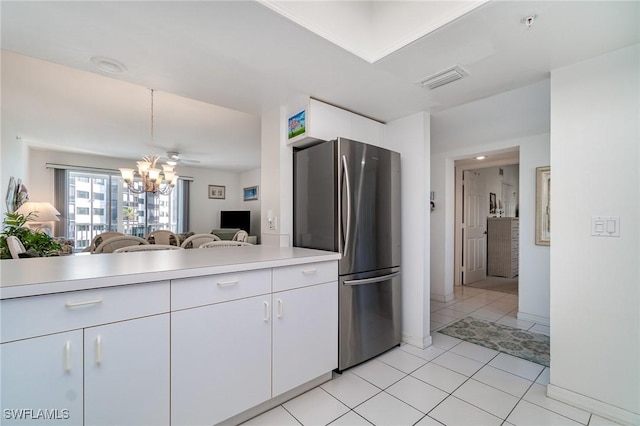 kitchen with stainless steel refrigerator, a notable chandelier, light tile patterned flooring, and white cabinets