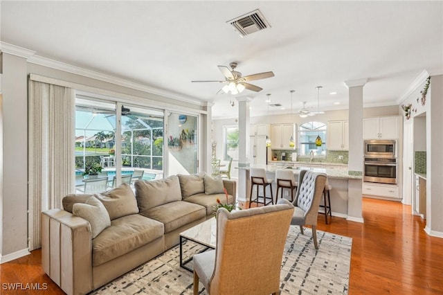 living room featuring ceiling fan, ornamental molding, sink, and light hardwood / wood-style flooring