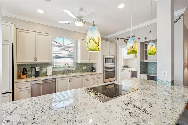 kitchen with sink, light stone counters, washer and dryer, stainless steel appliances, and decorative backsplash