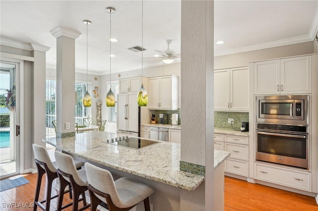 kitchen featuring appliances with stainless steel finishes, white cabinets, decorative backsplash, hanging light fixtures, and light stone countertops