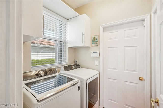 clothes washing area with washing machine and dryer and cabinets