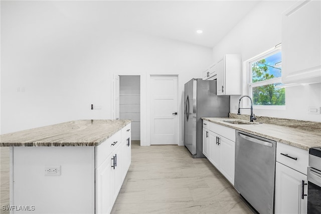 27141 Alhambra Dr, Punta Gorda, FL 33955 - kitchen with appliances with stainless steel finishes, white cabinetry, vaulted ceiling, light marble finish floors, and a center island