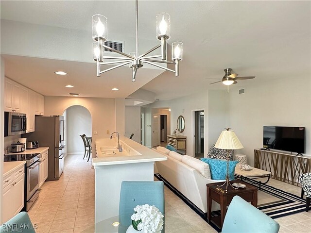 kitchen featuring appliances with stainless steel finishes, decorative light fixtures, white cabinetry, sink, and a kitchen island with sink